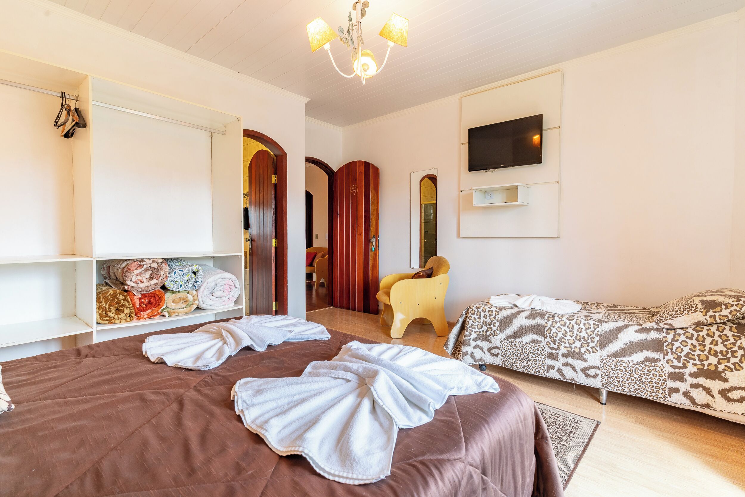 A hotel room with a large bed, a sofa, a TV mounted on the wall, and a wardrobe.