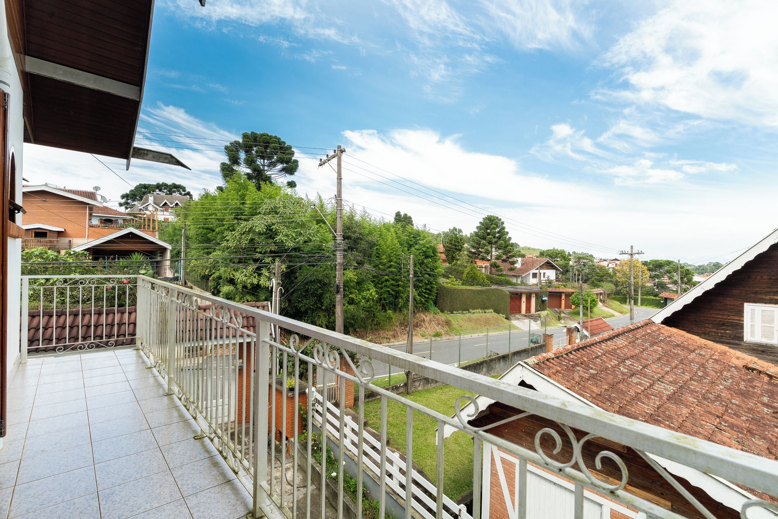 A balcony with a metal railing overlooking a residential street.
