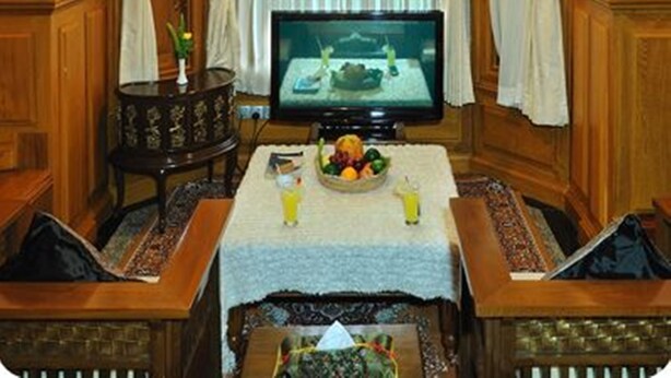 A cozy living room with a television, wooden furniture, and a table with fruit and drinks. - Royal Reward Resort (Pyin Oo Lwin)