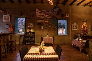 A rustic restaurant interior with wooden furniture, checkered tablecloths, and a mural of a bird. - La Confianza Hotel (Lunahuana)
