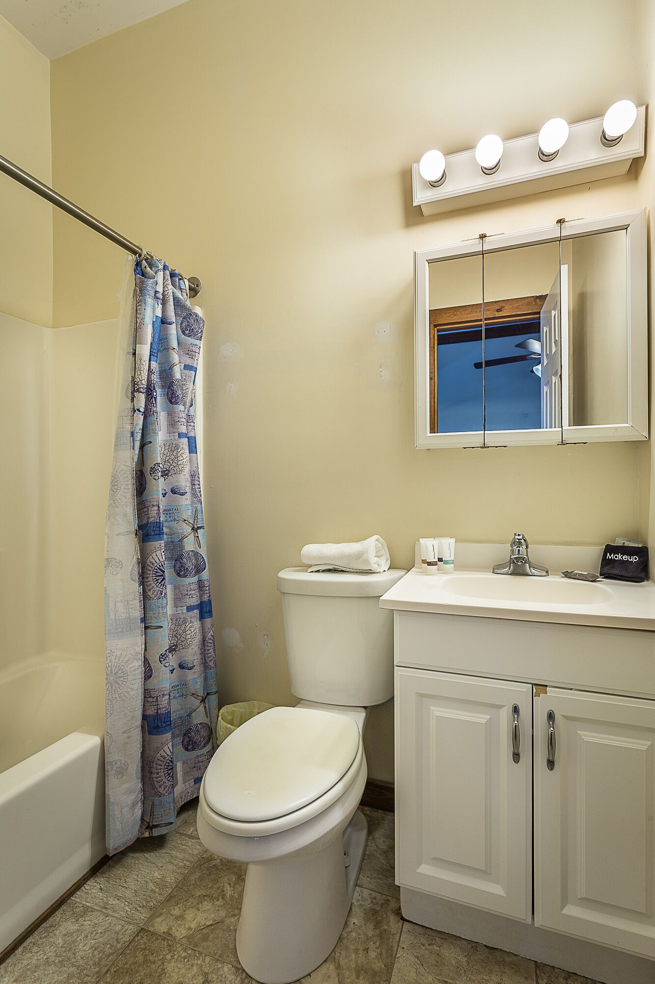A bathroom with a toilet, sink, mirror, and shower curtain.