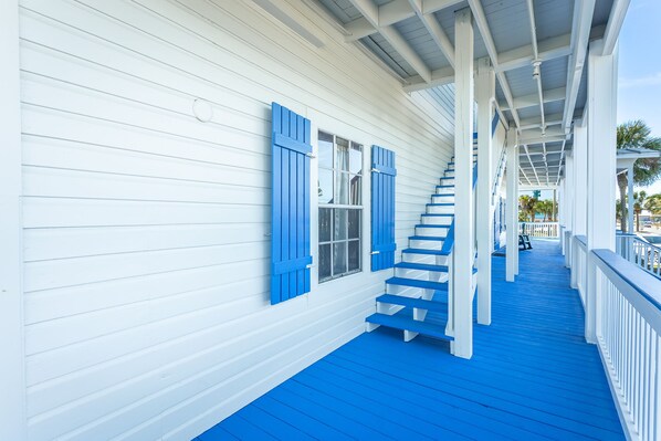 A covered porch with blue steps leading to a white door.