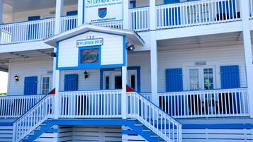 A multi-story hotel with a blue and white exterior, featuring balconies and a sign indicating it is open.