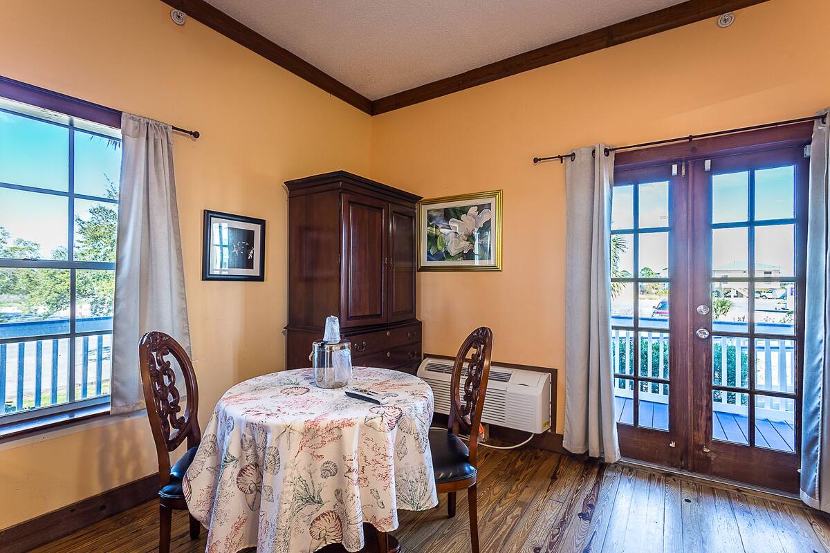 Un coin repas avec une table dressée pour deux personnes, un buffet en bois et un radiateur.