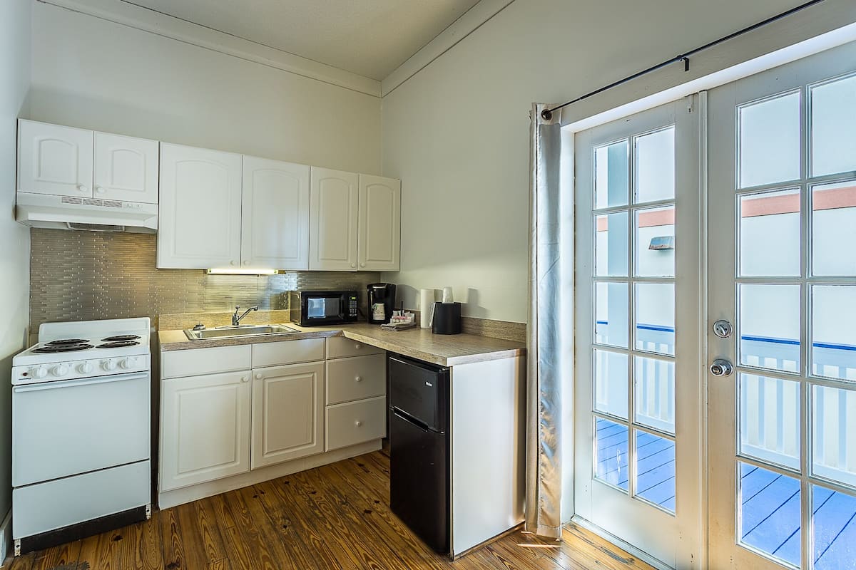 Une cuisine de taille réduite avec des meubles blancs, une cuisinière, un four à micro-ondes et un lave-vaisselle.