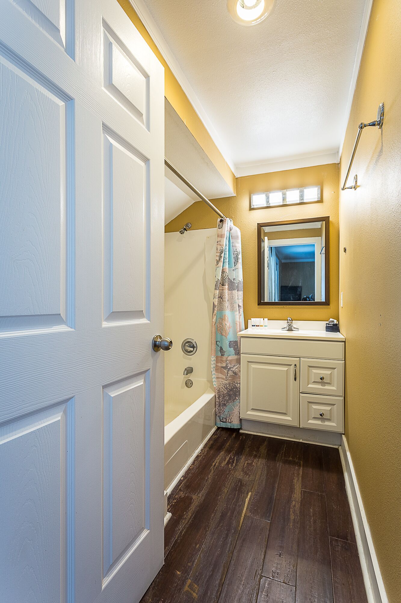 A bathroom with a bathtub, a shower, and a vanity with a mirror.