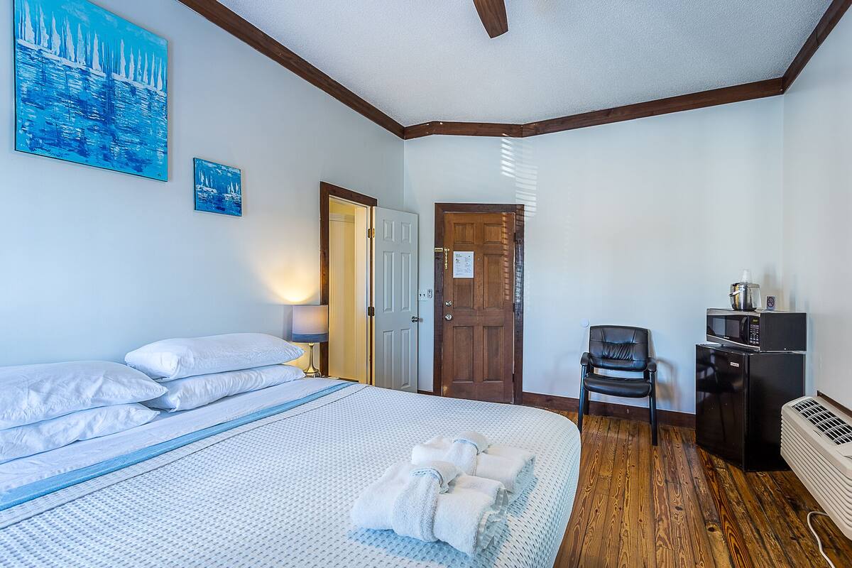 Une chambre avec un lit, une chaise, un bureau et un four à micro-ondes.