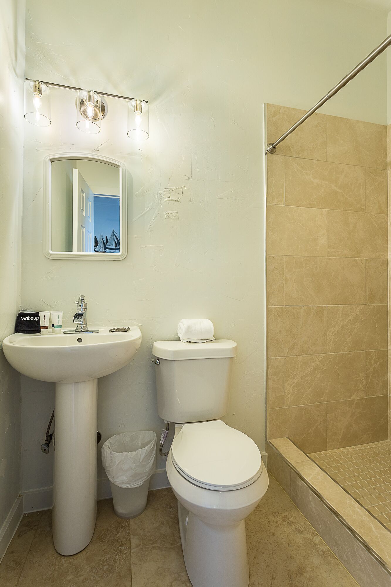 Un baño con lavamanos, espejo, inodoro y ducha.