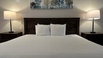 A neatly made bed with two pillows, flanked by two bedside tables with lamps, and a painting above the bed.