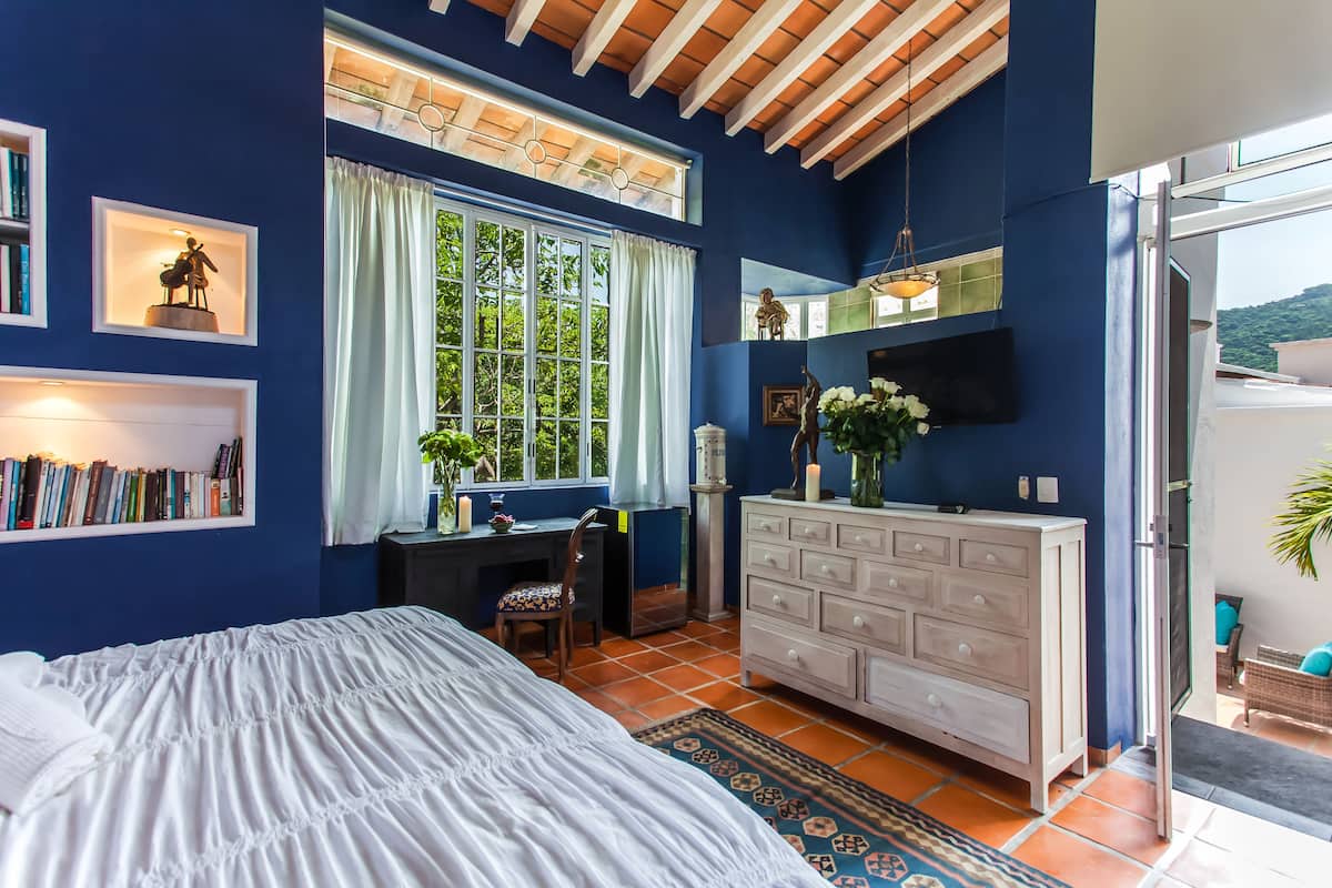 Un dormitorio con cama, escritorio, cómoda y televisor.