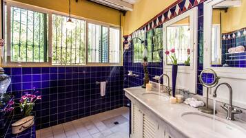 A bathroom with a large window, a sink, and a mirror.