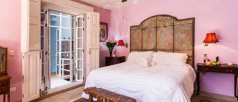 A bedroom with a bed, a bench, a nightstand, a lamp, and a ceiling fan.