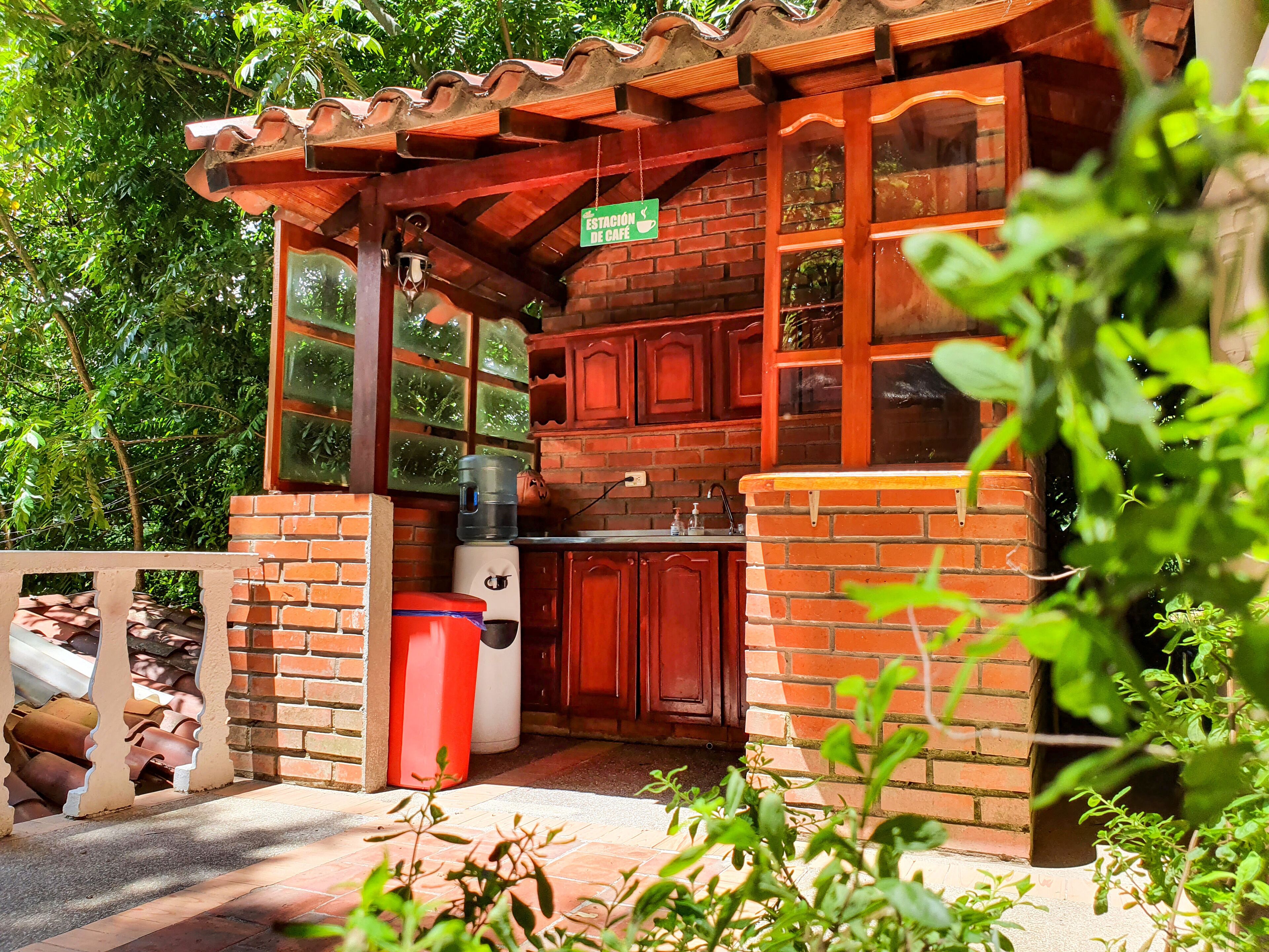 A rustic outdoor kitchen with brick walls, wooden cabinets, and a tiled roof.