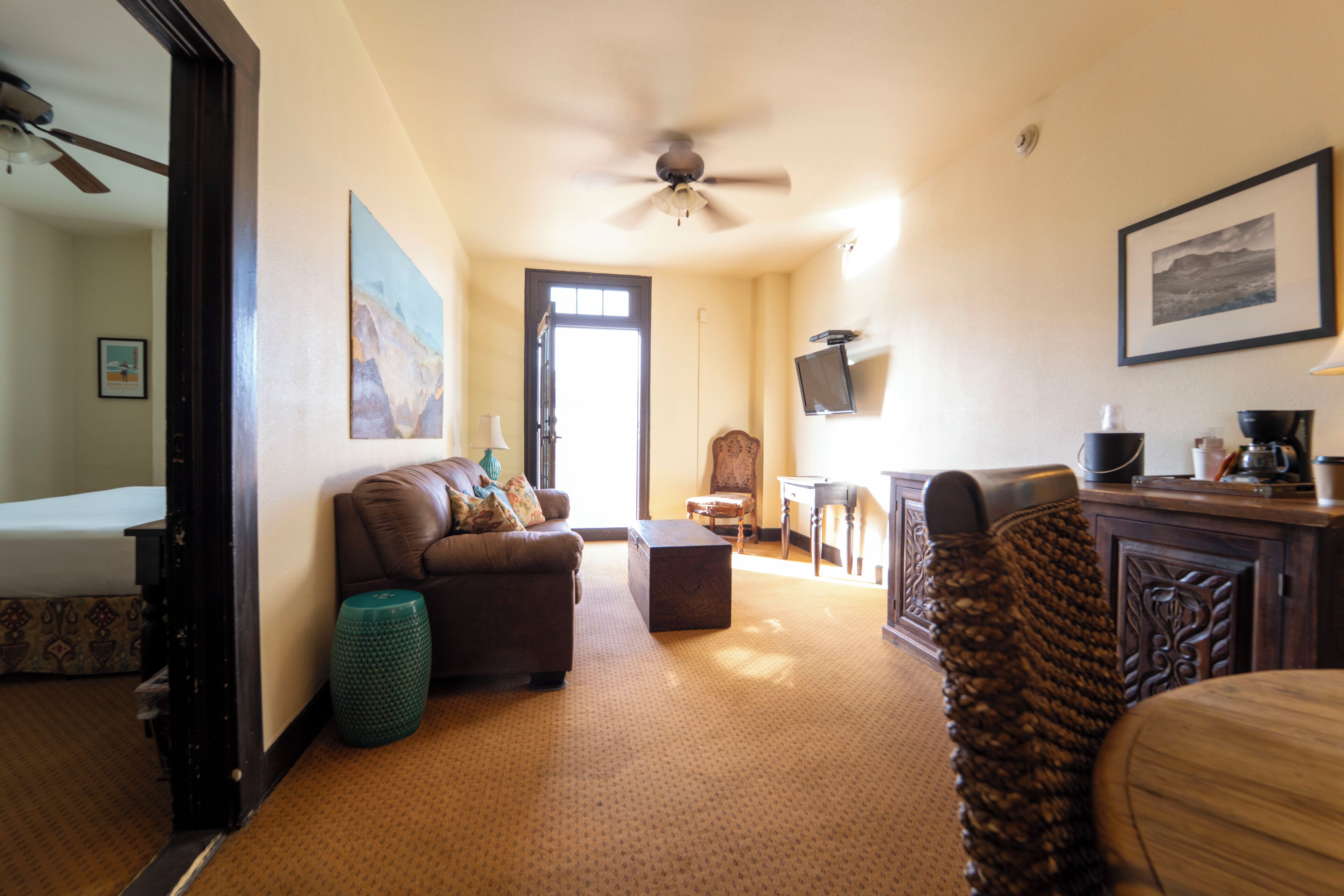 A hotel room with a sofa, a coffee table, a television, and a ceiling fan.