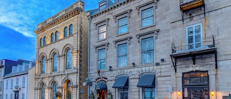 A row of historic buildings with large windows and ornate facades.