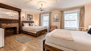 A hotel room with two beds, a fireplace, large windows, and artwork on the walls. - North House - Auberge la chouette / Hôtel Automatisé (Québec City)