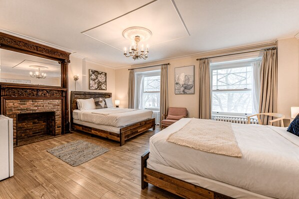 A hotel room with two beds, a fireplace, large windows, and artwork on the walls. - North House - Auberge la chouette / Hôtel Automatisé (Québec City)