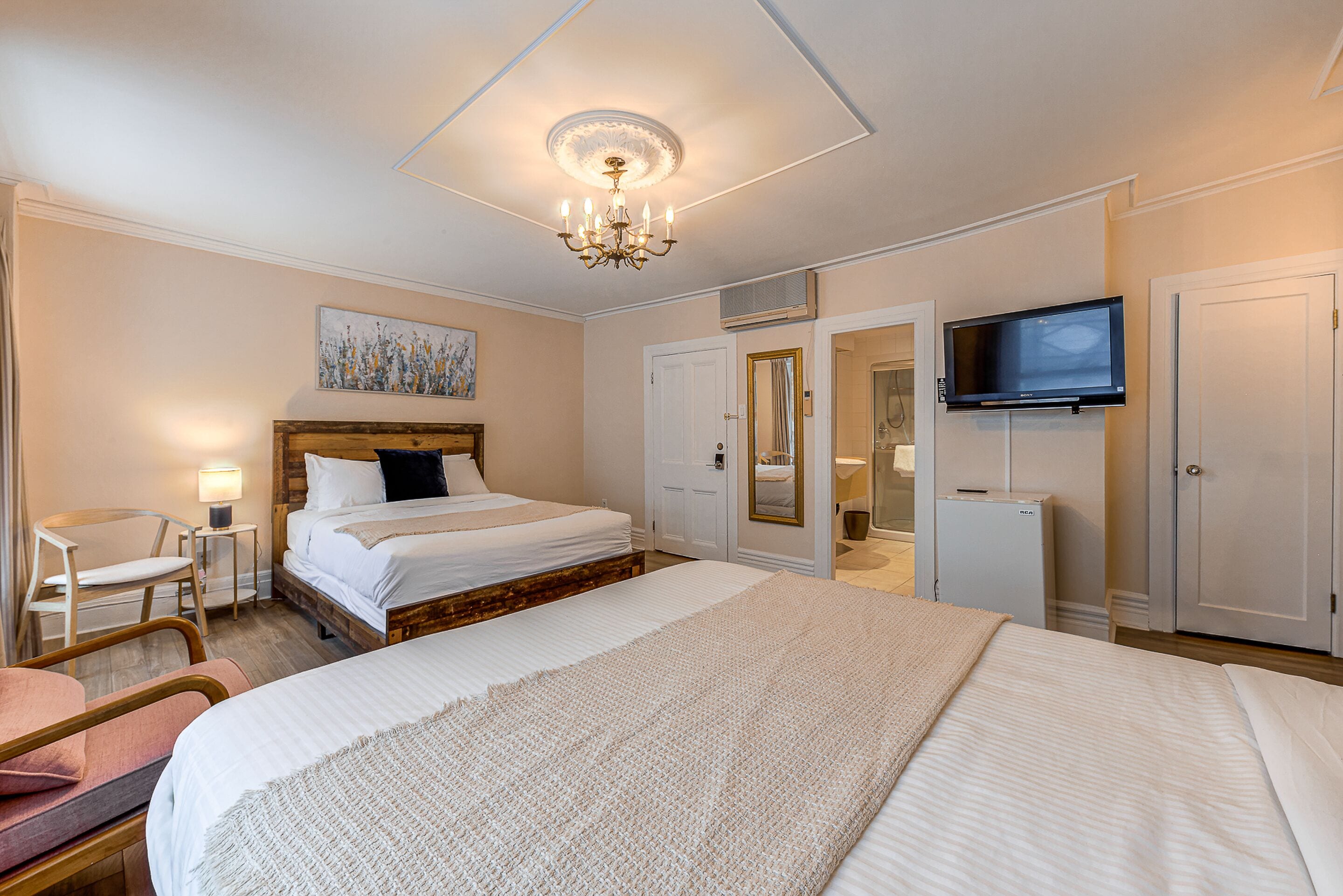 A hotel room with a large bed, a TV, a desk, and a chair.