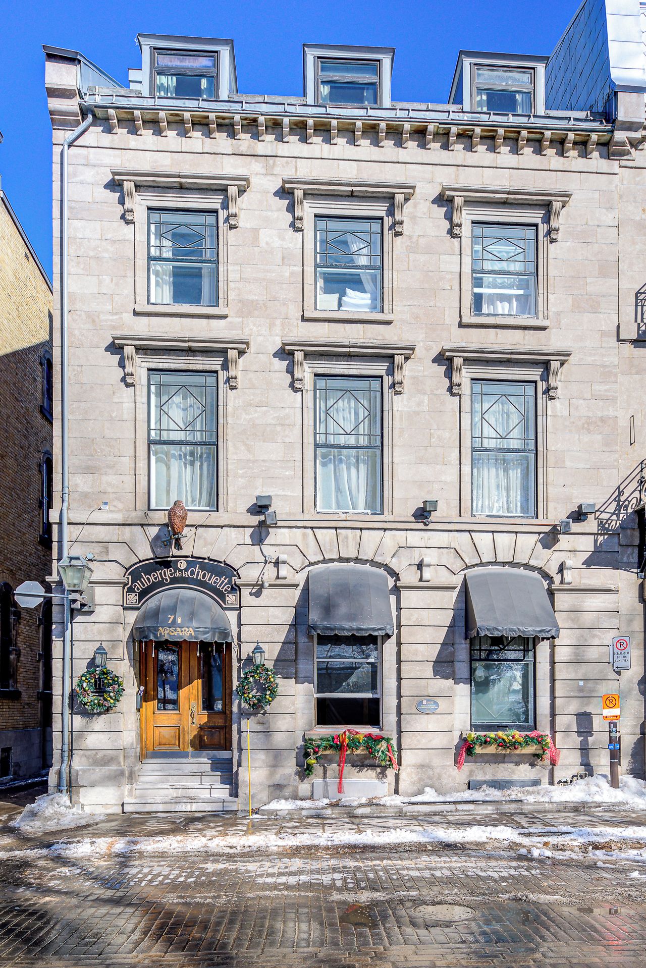 A two-story building with a ground-floor entrance, a sign above the door, and a small awning over the entrance.