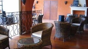 Un hall d’entrée avec des meubles en osier, une cheminée et un balcon doté d’une balustrade.