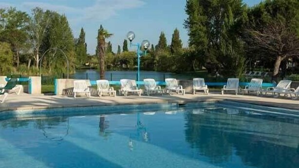 Une piscine bordée de chaises longues blanches, sous un ciel d’un bleu limpide.