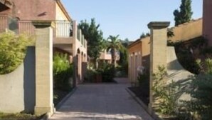 Une rue résidentielle bordée de maisons des deux côtés, avec un trottoir pavé et de la verdure.