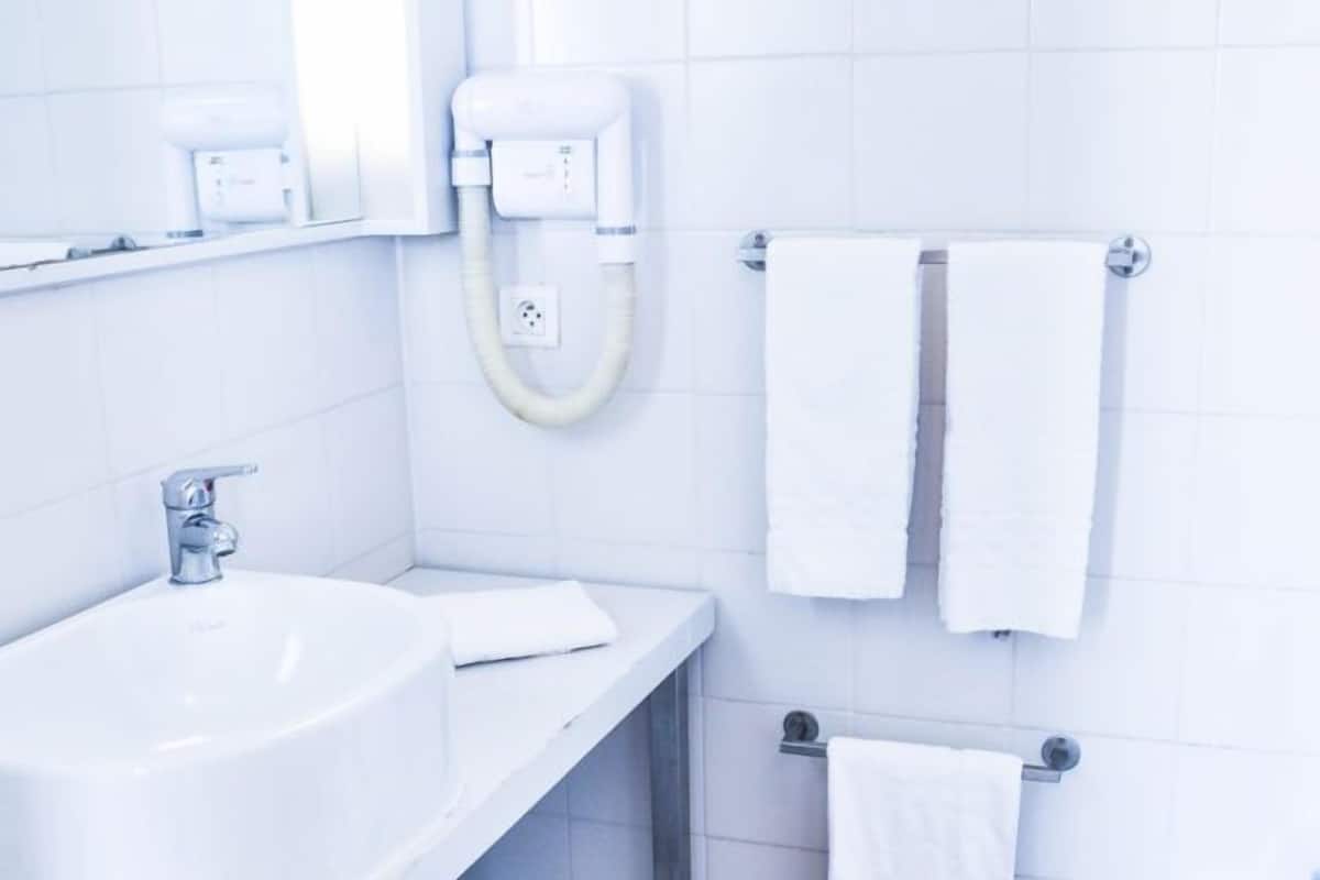 Ein modernes Badezimmer mit zwei Waschbecken, einem Spiegel, einem Handtuchhalter und einem Mülleimer.