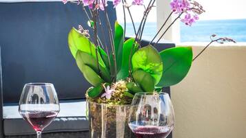 A wicker table with two wine glasses and a potted orchid plant.