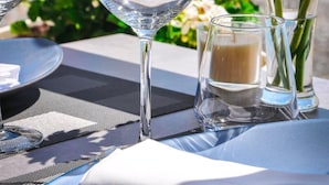 A table set with clear glasses, a blue plate, and a candle.