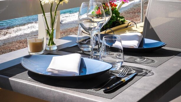 A table set for two with a view of the sea and buildings in the background.