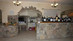 A stone bar area with wine bottles and a fireplace. - Funtana Abbas (Luras)