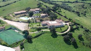 An aerial view of a large estate with multiple buildings, a tennis court, and surrounding green fields. - Funtana Abbas (Luras)
