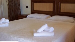 A neatly made bed with white linens and pillows, a wooden headboard, and a wall-mounted nightstand with a lamp. - Funtana Abbas (Luras)