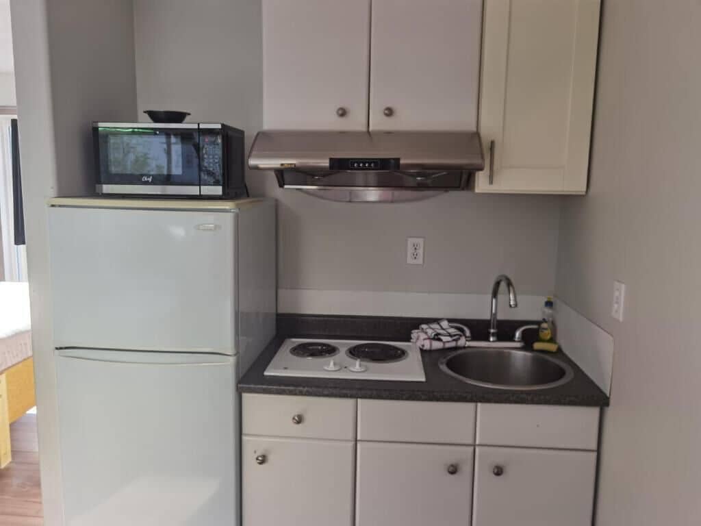 Une cuisine compacte équipée d’un réfrigérateur, d’un four à micro-ondes, d’une cuisinière, d’un évier et de placards.