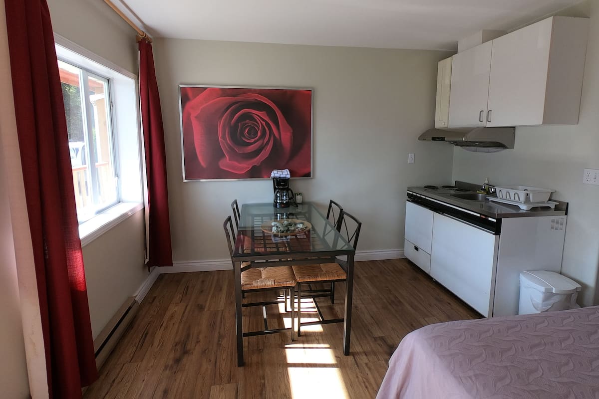 A compact kitchen with a dining table, chairs, a coffee maker, and a stove.