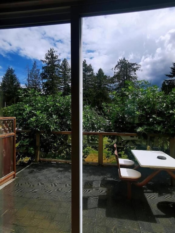An outdoor patio with a table and chairs, surrounded by dense greenery and trees. - Qualicum Bay Resort (Qualicum Beach)