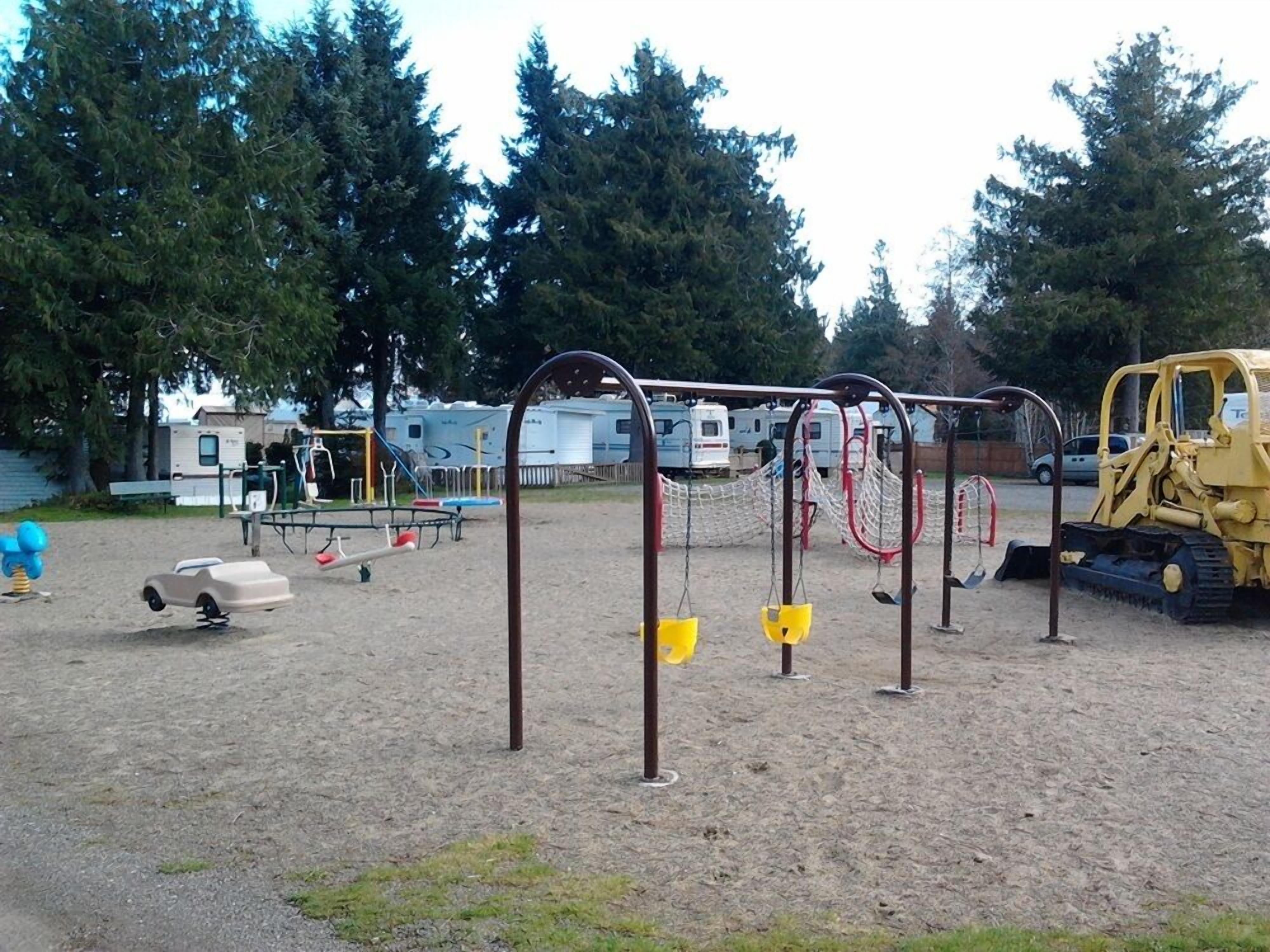 A playground with swings, a seesaw, and a small car ride.