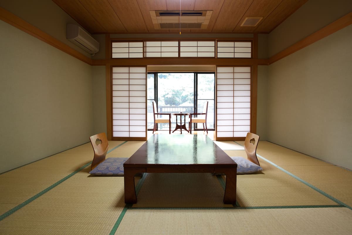 Una habitación tradicional japonesa con suelo de tatami, una mesa de madera baja y puertas correderas shoji.