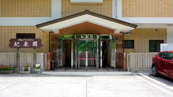 A hotel entrance with a revolving door, a signboard, and a red car parked outside.
