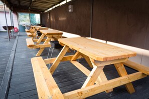A row of wooden picnic tables with benches, arranged on a wooden deck under a covered area. - Seorak Hot Spring Mammoth Resotel (Sokcho)