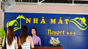 Un comptoir d’accueil avec l’enseigne « NHAMAT Resort » et un logo représentant un palmier.