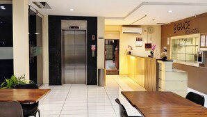 A hotel lobby with a reception desk, a clock, and a digital elevator display. - Grace Setia Hotel (Surabaya)