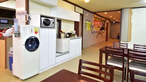 Una cocina compacta con microondas, dispensador de agua y un pequeño comedor con sillas de madera.