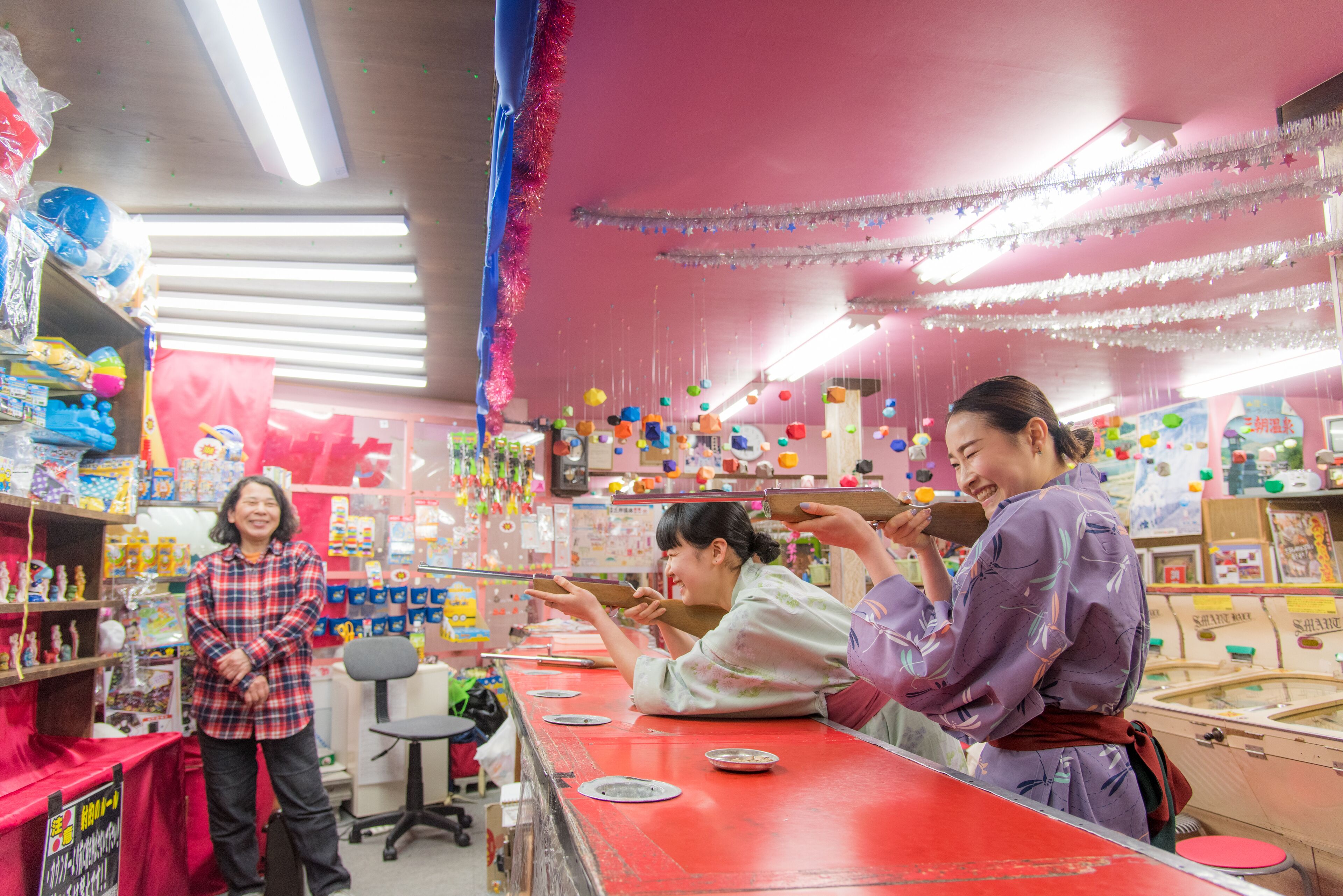 Una tienda luminosa con estantes llenos de juguetes y juegos, un mostrador rojo y decoraciones festivas.