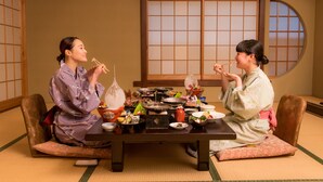 A traditional Japanese room with tatami flooring, a low table with various dishes, and sliding doors. - Iwayu Ryokan (Misasa)
