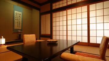 Una habitación japonesa tradicional con suelo de tatami, una mesa baja y puertas correderas.