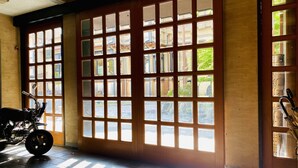 A room with large windows, a motorcycle, and a broom leaning against the wall. - Iwayu Ryokan (Misasa)