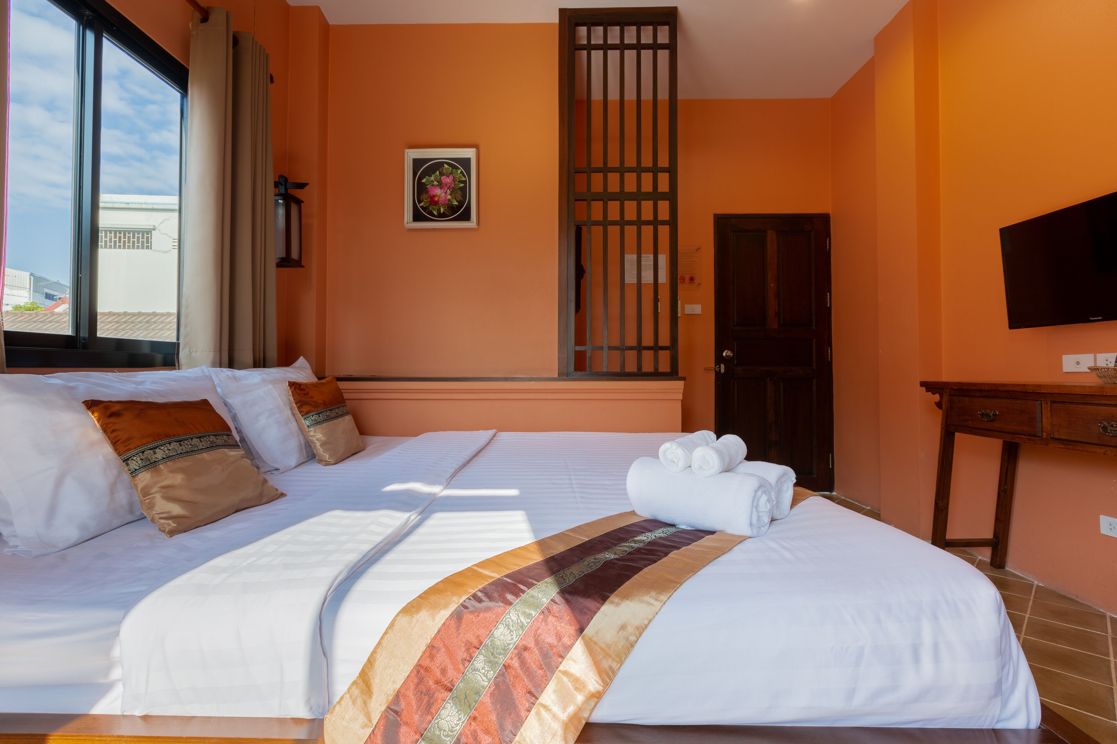 A hotel room with a large bed, a television, and a window with curtains.