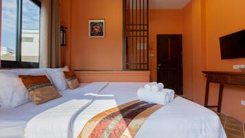A hotel room with a large bed, a television, and a window with curtains.