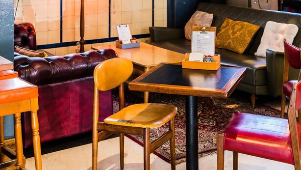 A modern interior with a wooden slat wall, a sofa, a table, and a plant. - Darlo Bar Darlinghurst (Darlinghurst)